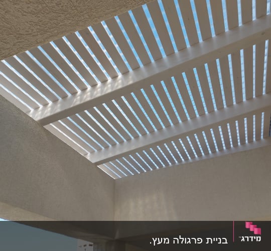 פרגולה מעץ לבן עם חריצים לאור השמש
